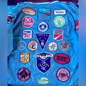 Vintage Marksmanship patches and gun club patches on blue windbreaker.